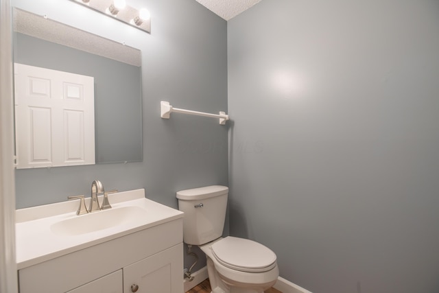 bathroom with a textured ceiling, toilet, and vanity