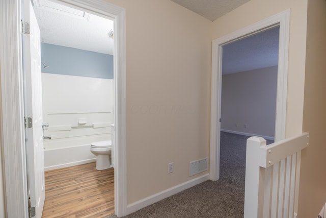 corridor featuring light colored carpet and a textured ceiling