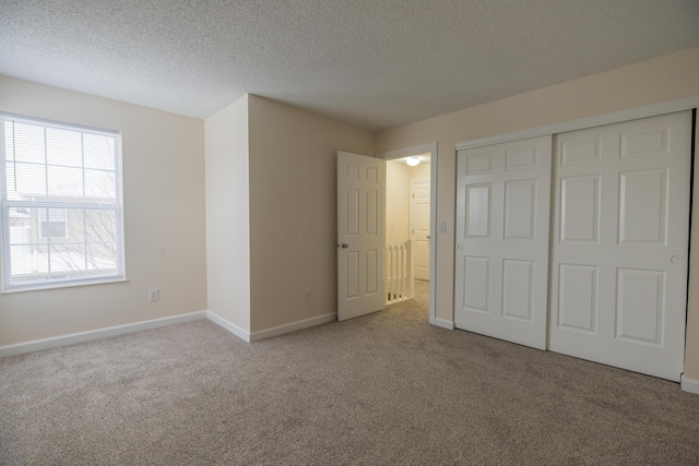 unfurnished bedroom featuring a textured ceiling, light colored carpet, and a closet