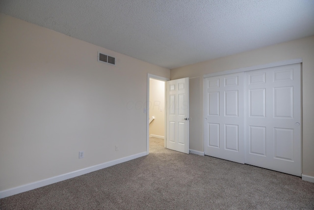 unfurnished bedroom featuring a textured ceiling, light colored carpet, and a closet