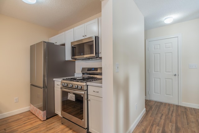 kitchen with white cabinets, stainless steel appliances, light hardwood / wood-style flooring, and a textured ceiling