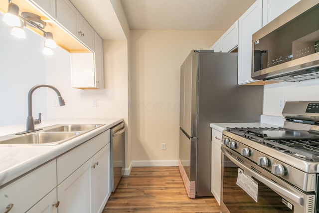 kitchen with white cabinets, appliances with stainless steel finishes, light hardwood / wood-style flooring, and sink