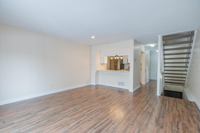 unfurnished living room featuring a textured ceiling and wood-type flooring