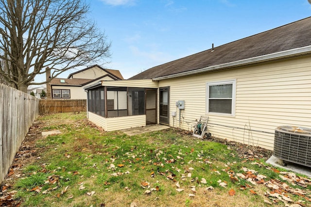 rear view of house with cooling unit, a lawn, and a sunroom