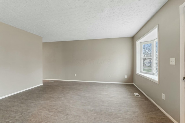 unfurnished room with a textured ceiling and dark hardwood / wood-style flooring