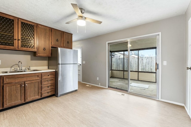 kitchen featuring stainless steel fridge, sink, ceiling fan, and light wood-type flooring