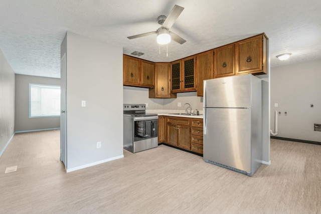 kitchen with a textured ceiling, stainless steel appliances, light hardwood / wood-style floors, and sink