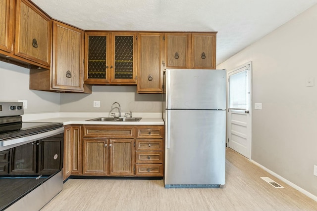 kitchen with sink, stainless steel appliances, and light hardwood / wood-style floors