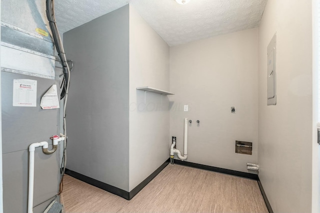 washroom with light wood-type flooring, a textured ceiling, and heating unit