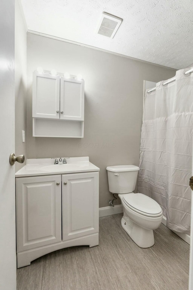 bathroom featuring hardwood / wood-style flooring, vanity, toilet, and a textured ceiling