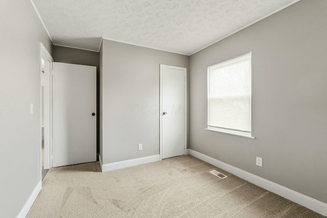 unfurnished bedroom with a textured ceiling and light carpet