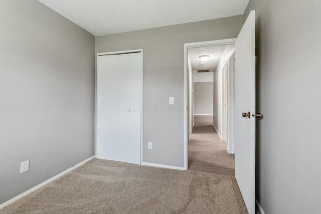 unfurnished bedroom with a closet, carpet, and a textured ceiling