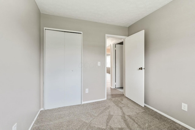 unfurnished bedroom with light colored carpet, a textured ceiling, and a closet