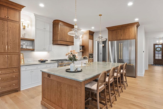 kitchen with decorative backsplash, high quality appliances, a breakfast bar area, light wood-style floors, and open shelves