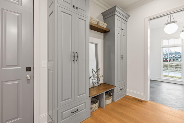 mudroom featuring light wood-style flooring, visible vents, ornamental molding, and baseboards