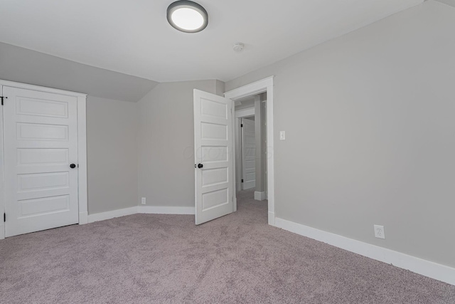 additional living space featuring light colored carpet and lofted ceiling