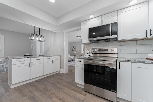 kitchen featuring backsplash, white cabinets, hanging light fixtures, light wood-type flooring, and appliances with stainless steel finishes