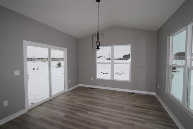 unfurnished dining area featuring an inviting chandelier, vaulted ceiling, and dark hardwood / wood-style floors