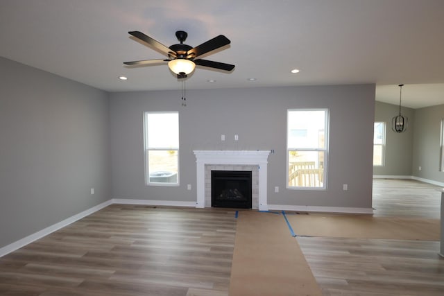 unfurnished living room with a tiled fireplace, recessed lighting, wood finished floors, and baseboards