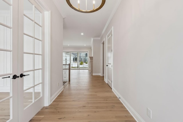 hallway featuring a notable chandelier, french doors, ornamental molding, and light hardwood / wood-style floors