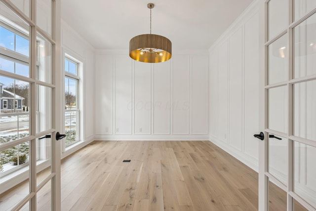 unfurnished dining area featuring crown molding and light hardwood / wood-style flooring