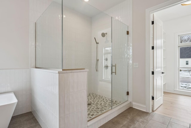 bathroom with plus walk in shower, tile patterned flooring, and tile walls