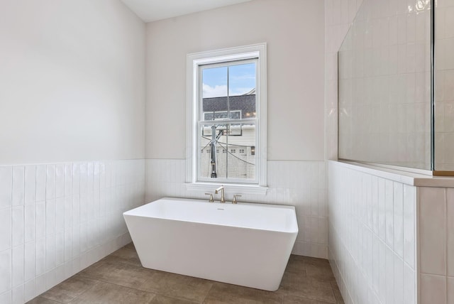 bathroom featuring tile patterned floors, a bathtub, and tile walls