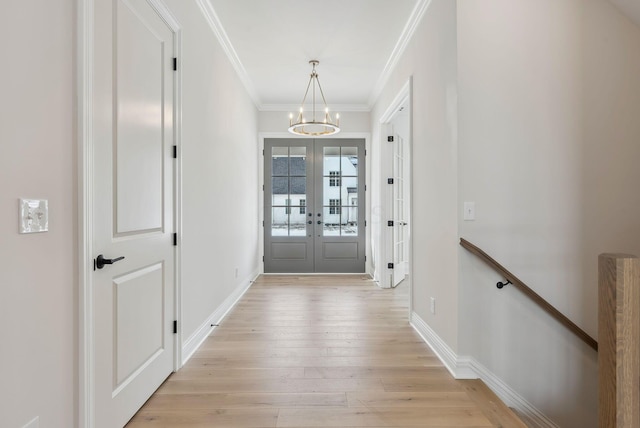 entryway featuring a notable chandelier, french doors, crown molding, and light hardwood / wood-style floors