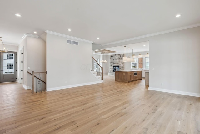 unfurnished living room with a fireplace, ornamental molding, a chandelier, and light wood-type flooring