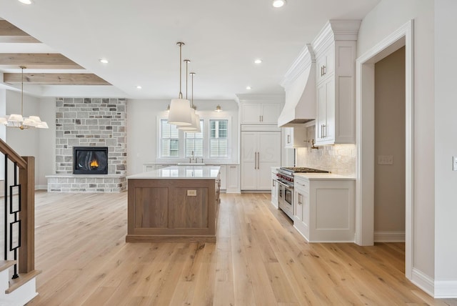 kitchen with premium appliances, pendant lighting, custom exhaust hood, white cabinetry, and a center island