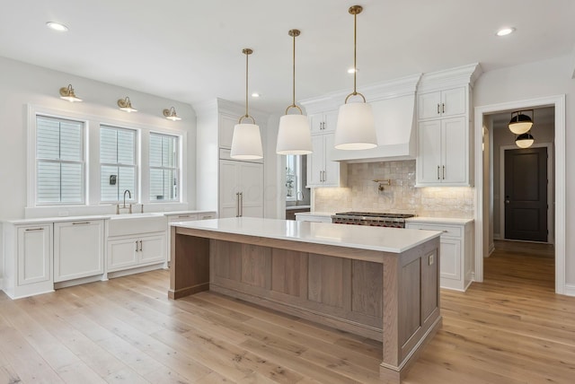 kitchen featuring sink, a center island, light hardwood / wood-style flooring, and white cabinetry