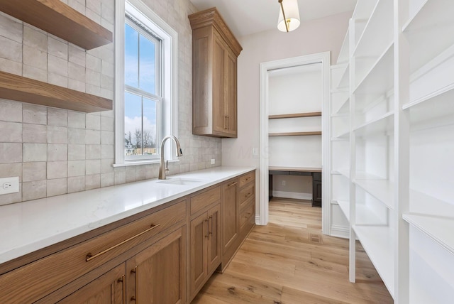 kitchen with sink, a healthy amount of sunlight, light hardwood / wood-style flooring, and tasteful backsplash