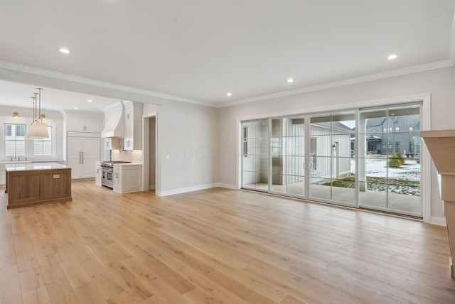 unfurnished living room with crown molding and light wood-type flooring