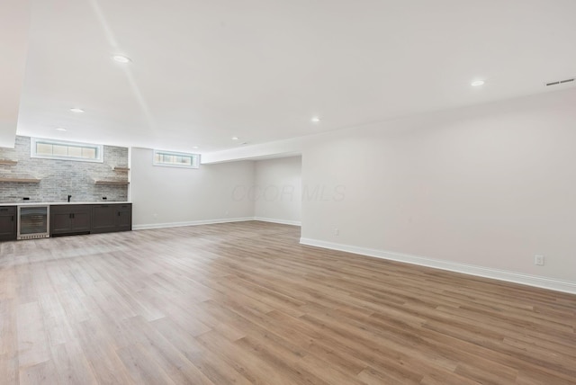 unfurnished living room featuring light hardwood / wood-style floors, wine cooler, and sink