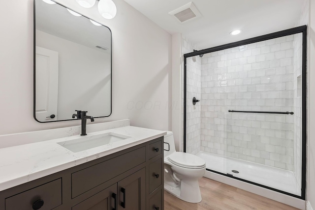 bathroom with hardwood / wood-style flooring, toilet, vanity, and an enclosed shower