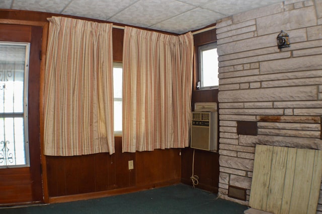 spare room with dark carpet, a drop ceiling, and wood walls