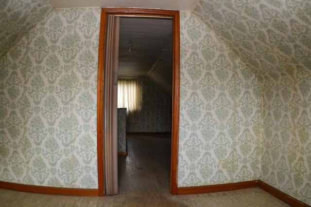 corridor featuring carpet flooring and vaulted ceiling