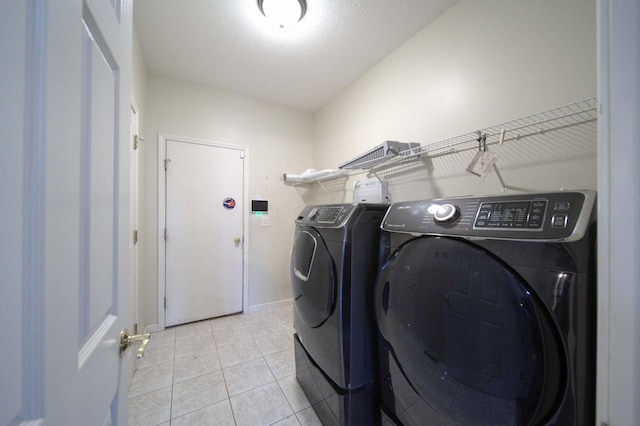 laundry area featuring laundry area, a textured ceiling, washing machine and clothes dryer, and light tile patterned floors