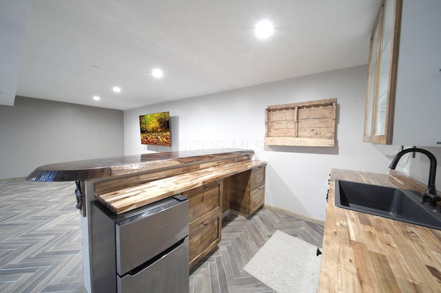 kitchen featuring butcher block counters, a sink, and recessed lighting