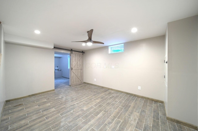 basement with baseboards, a barn door, wood finished floors, and recessed lighting