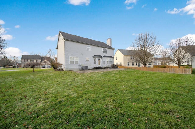 rear view of house featuring a patio, central AC unit, fence, a lawn, and a chimney