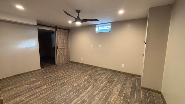 basement with recessed lighting, a barn door, wood tiled floor, ceiling fan, and baseboards