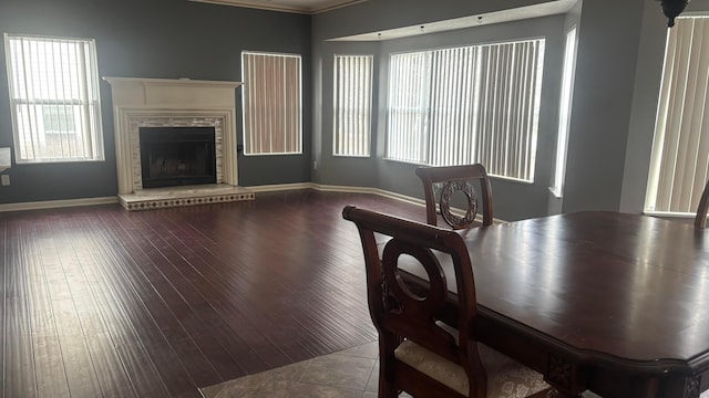 dining space featuring a fireplace with raised hearth, baseboards, and wood finished floors