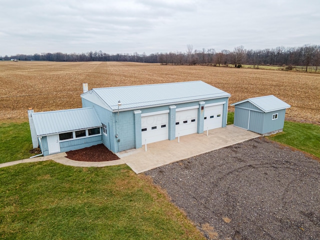 view of front of home with a rural view, a garage, a front lawn, and an outdoor structure