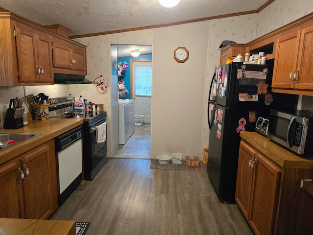 kitchen featuring sink, dark wood-type flooring, washing machine and dryer, appliances with stainless steel finishes, and ornamental molding