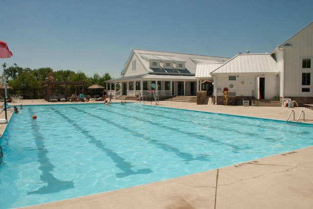 pool featuring a sunroom, a patio area, and a pergola