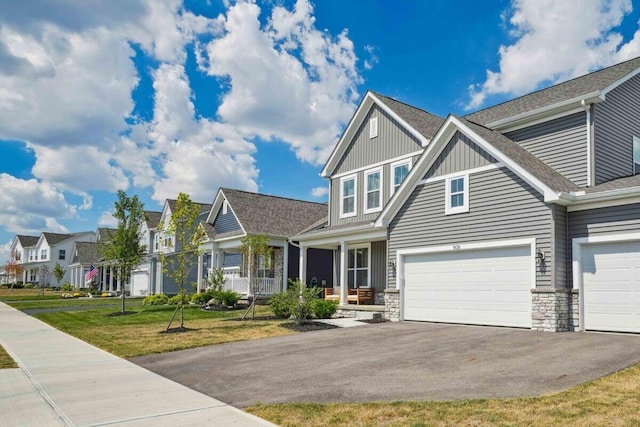 craftsman inspired home featuring aphalt driveway, board and batten siding, a garage, a residential view, and a front lawn