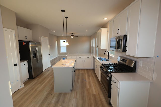 kitchen featuring light countertops, appliances with stainless steel finishes, light wood-style floors, a sink, and a kitchen island