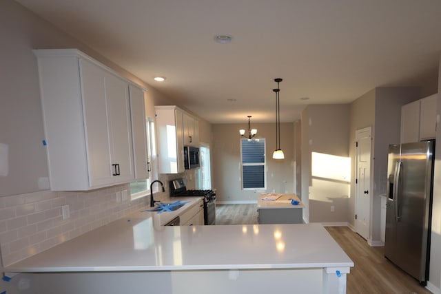 kitchen with decorative backsplash, stainless steel appliances, light countertops, light wood-style floors, and a sink