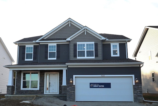 craftsman-style home with a garage, stone siding, and driveway